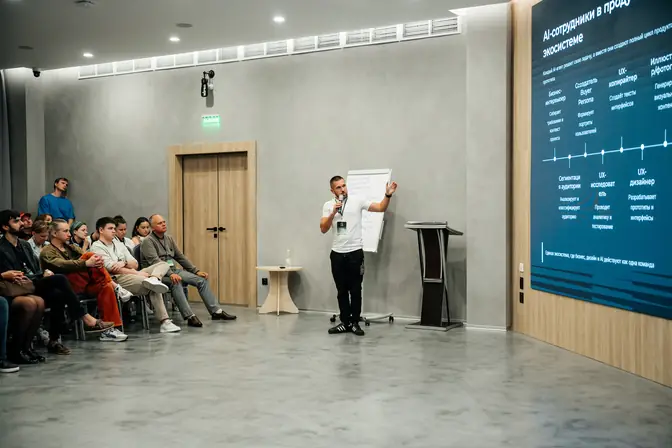 Денис Бугров у экрана со слайдом на IT Talk by Sber
