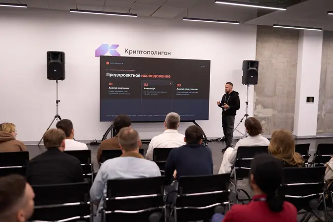 Денис Бугров у экрана с презентацией на площадке Криптополигон